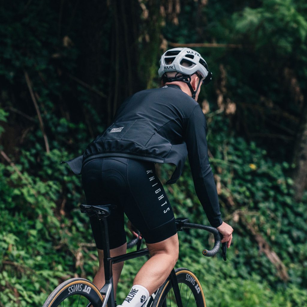 Man riding a bike in the forest wearing a black cycling jacket
